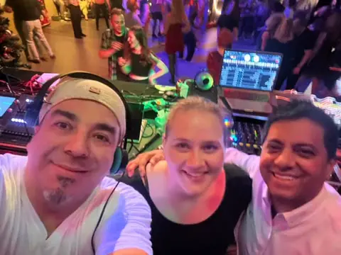 DJ Vlady with guests at the DJ booth at a Latin party
